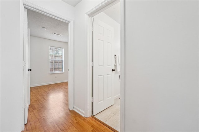 hall featuring a textured ceiling and light wood-type flooring