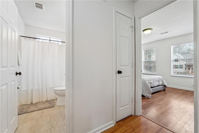 bathroom featuring hardwood / wood-style flooring, toilet, a textured ceiling, and shower / bath combo with shower curtain