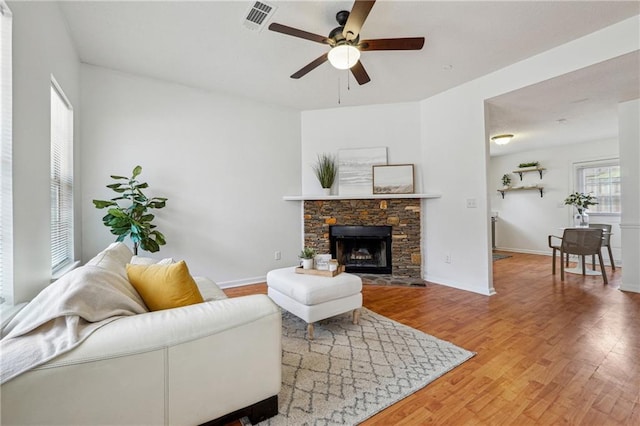 living room featuring ceiling fan, hardwood / wood-style floors, and a fireplace