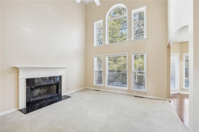 unfurnished living room with a towering ceiling, light carpet, and a fireplace