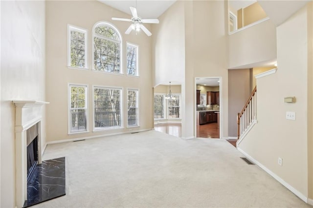 unfurnished living room with a towering ceiling, a high end fireplace, and carpet flooring