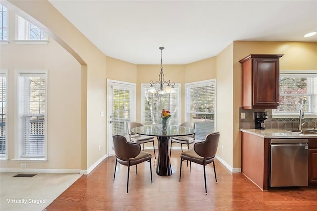 dining room with plenty of natural light, a chandelier, sink, and wood-type flooring