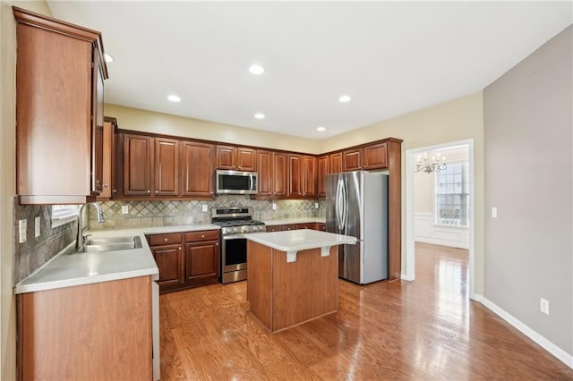 kitchen with sink, backsplash, stainless steel appliances, a center island, and light wood-type flooring