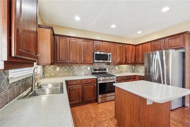 kitchen featuring sink, backsplash, stainless steel appliances, light hardwood / wood-style floors, and a kitchen bar