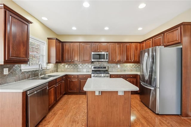 kitchen with appliances with stainless steel finishes, light hardwood / wood-style floors, sink, and a kitchen island