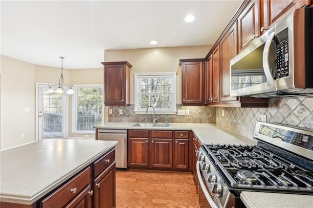 kitchen featuring sink, a chandelier, decorative backsplash, stainless steel appliances, and light hardwood / wood-style flooring