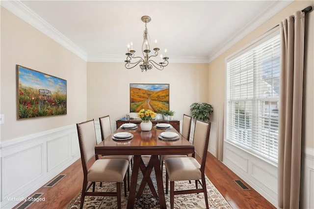 dining area featuring ornamental molding, wood-type flooring, plenty of natural light, and a notable chandelier