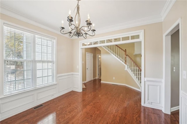 spare room with dark wood-type flooring, ornamental molding, and a chandelier