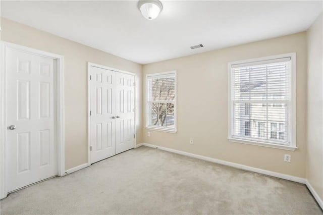 unfurnished bedroom featuring light carpet and multiple closets