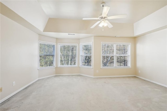 unfurnished room with a healthy amount of sunlight, light carpet, ceiling fan, and a tray ceiling