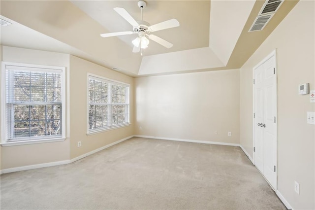 carpeted empty room featuring ceiling fan and a tray ceiling