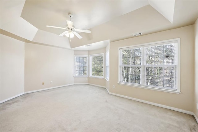 carpeted spare room with a raised ceiling and ceiling fan