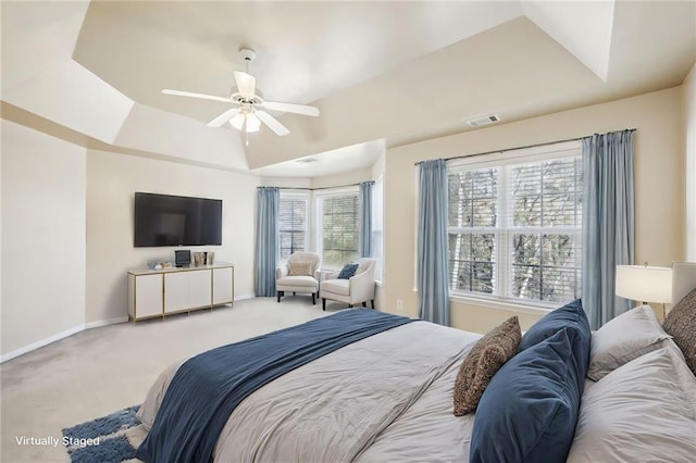 bedroom with ceiling fan, carpet flooring, and a raised ceiling