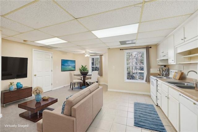 living room with a drop ceiling, sink, light tile patterned floors, and ceiling fan