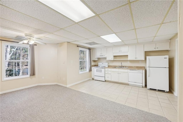 kitchen with a paneled ceiling, white cabinetry, sink, light tile patterned floors, and white appliances