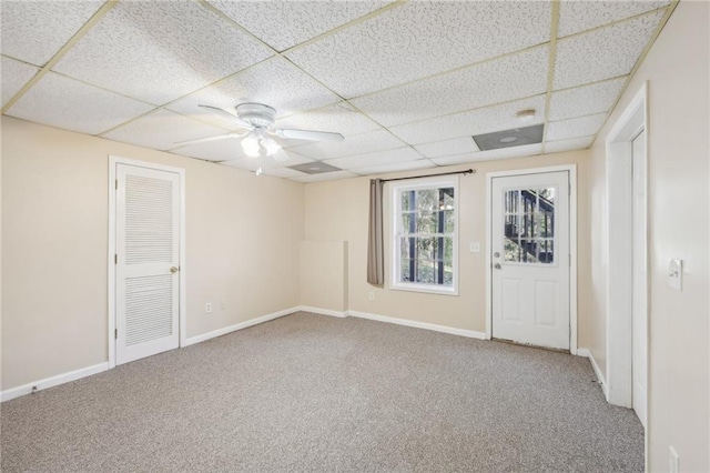 empty room with carpet, a drop ceiling, and ceiling fan