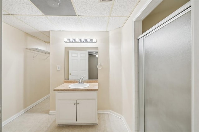 bathroom with walk in shower, a paneled ceiling, and vanity