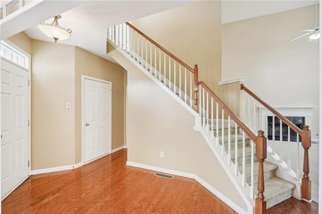 staircase featuring wood-type flooring and ceiling fan