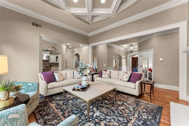 living room with coffered ceiling, wood-type flooring, ornamental molding, and beamed ceiling