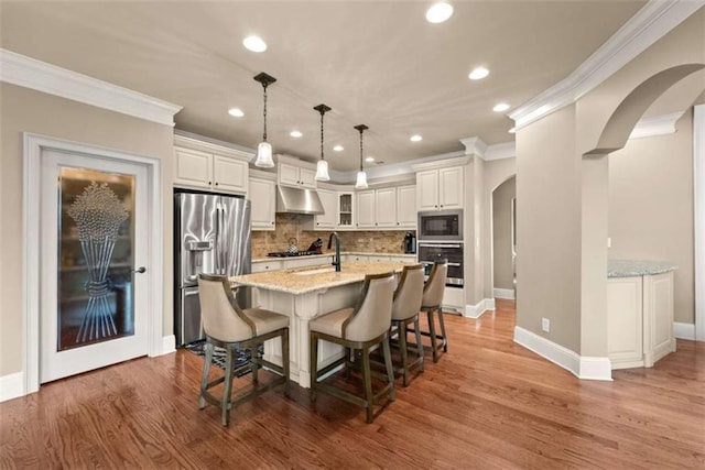 kitchen featuring white cabinetry, appliances with stainless steel finishes, light stone counters, and decorative light fixtures