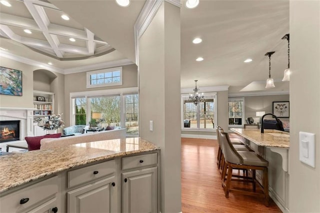 kitchen with coffered ceiling, light stone counters, crown molding, light wood-type flooring, and white cabinets