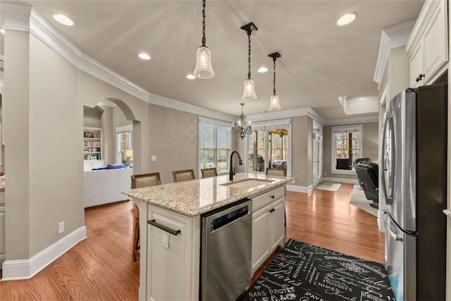 kitchen featuring white cabinetry, sink, a kitchen island with sink, stainless steel appliances, and light stone countertops