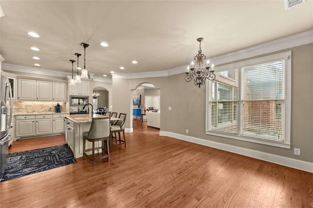 kitchen with pendant lighting, white cabinetry, a breakfast bar, and an island with sink