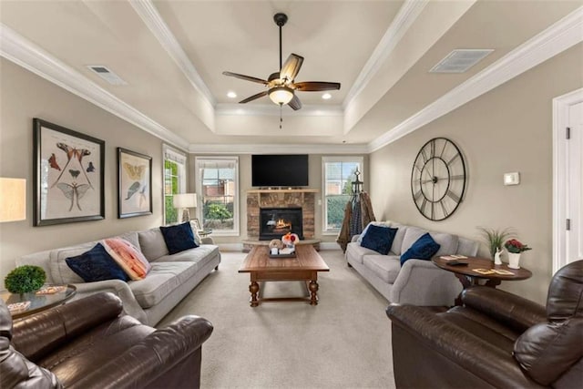 living room featuring crown molding, light colored carpet, a fireplace, and a raised ceiling