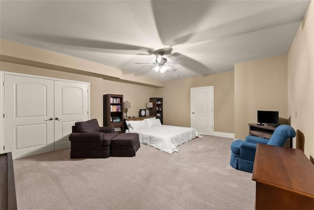 bedroom featuring light colored carpet, a closet, and ceiling fan