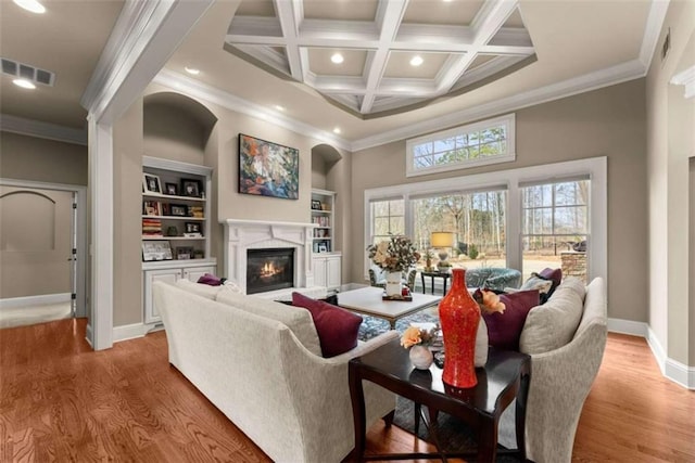 living room featuring coffered ceiling, ornamental molding, beamed ceiling, and light wood-type flooring