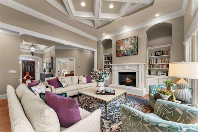 living room featuring hardwood / wood-style floors, beam ceiling, coffered ceiling, a fireplace, and ornamental molding