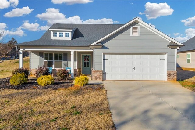 craftsman inspired home with covered porch, a garage, and a front lawn