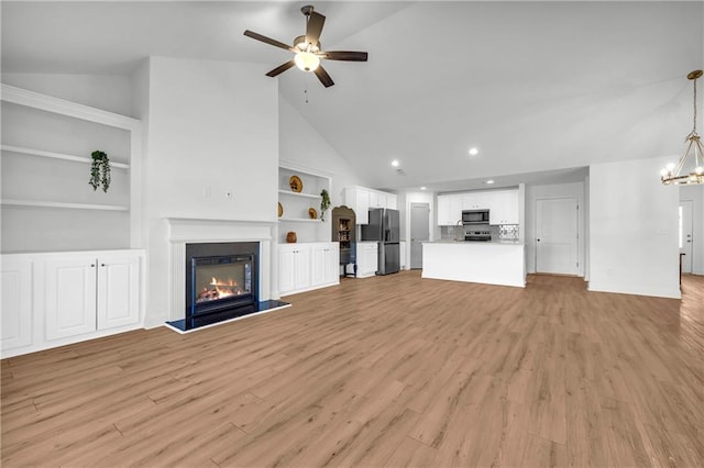 unfurnished living room with ceiling fan with notable chandelier, built in features, high vaulted ceiling, and light wood-type flooring