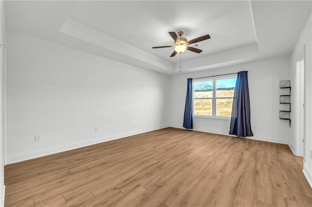 unfurnished room featuring ceiling fan, a tray ceiling, and light hardwood / wood-style flooring