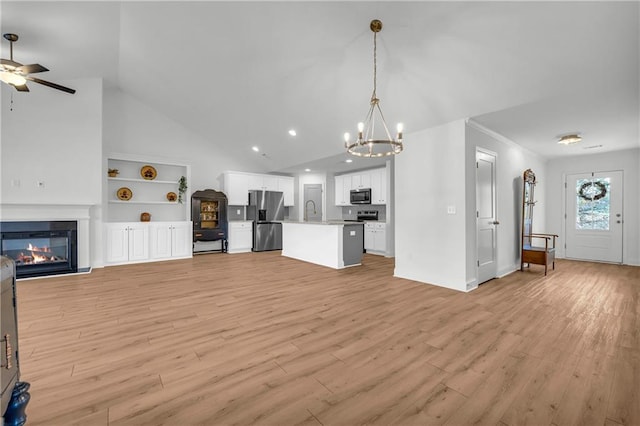 unfurnished living room featuring vaulted ceiling, sink, light hardwood / wood-style flooring, built in shelves, and ceiling fan with notable chandelier