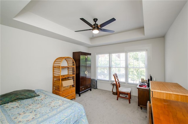 carpeted bedroom with ceiling fan and a raised ceiling