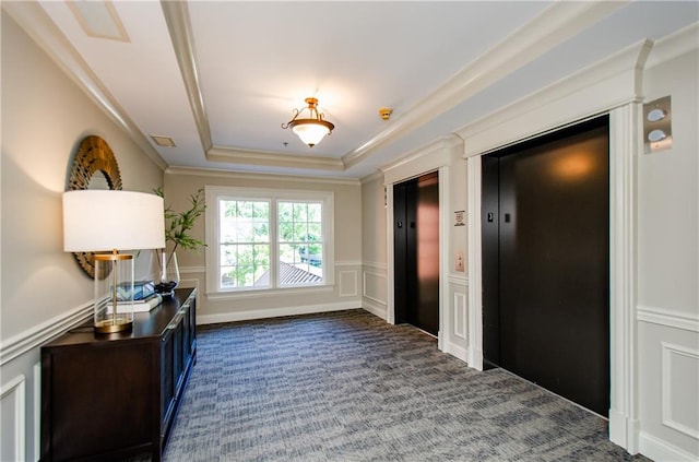 carpeted foyer entrance with elevator, crown molding, and a raised ceiling