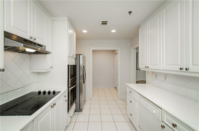 kitchen with appliances with stainless steel finishes, white cabinetry, light tile patterned floors, and backsplash