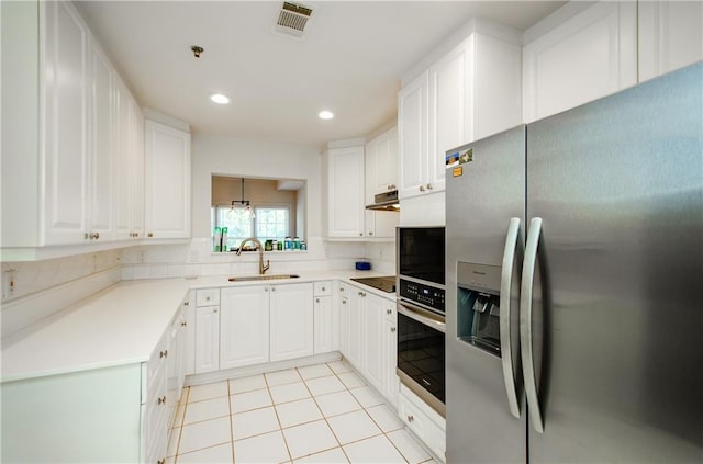 kitchen with light tile patterned flooring, stainless steel appliances, white cabinets, decorative backsplash, and sink