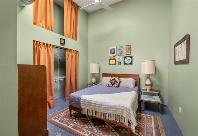 bedroom featuring finished concrete floors, a high ceiling, and a ceiling fan