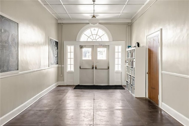 foyer entrance with french doors, concrete floors, and baseboards