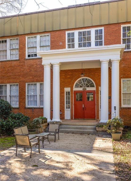 view of exterior entry featuring covered porch and brick siding