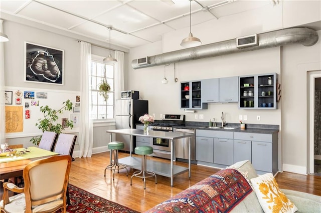 kitchen with visible vents, light wood-style flooring, stainless steel appliances, open shelves, and a sink