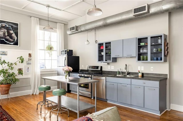 kitchen with stainless steel appliances, a sink, visible vents, open shelves, and dark countertops