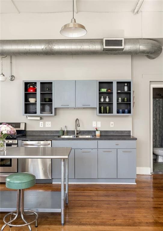 kitchen with a sink, visible vents, appliances with stainless steel finishes, open shelves, and dark countertops