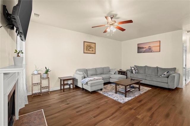 living area with ceiling fan, dark wood-type flooring, a premium fireplace, and baseboards