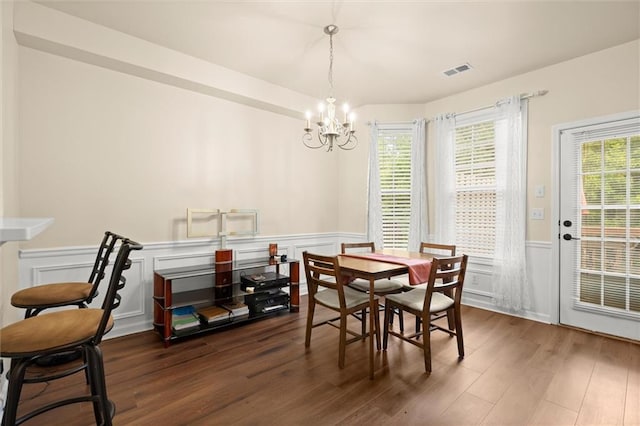dining area featuring a chandelier, a wainscoted wall, wood finished floors, and a decorative wall