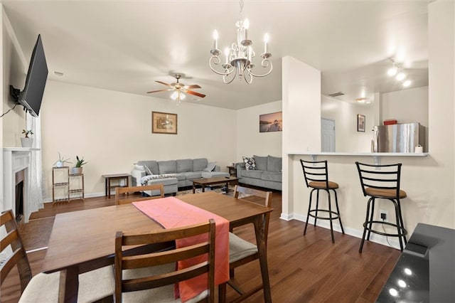 dining area featuring dark wood-style flooring, ceiling fan, baseboards, and a chandelier