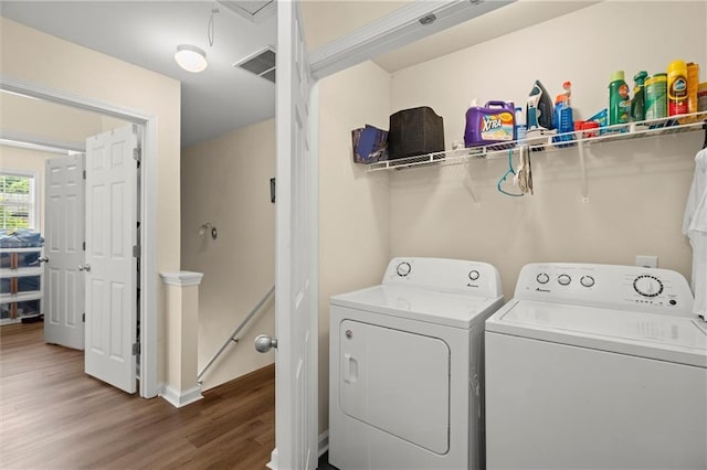laundry area with washer and clothes dryer, wood finished floors, baseboards, and attic access