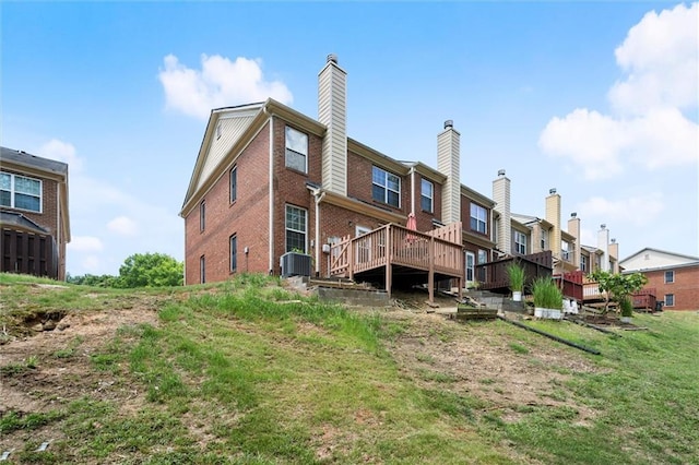 back of house with brick siding, a deck, central AC unit, a chimney, and a residential view
